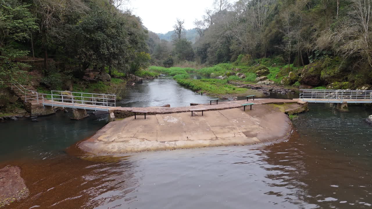 Aerial view of the Gruta India Natural Park, located in Misiones, Argentina, featuring the serene waterway and footbridge surrounded by lush greenery