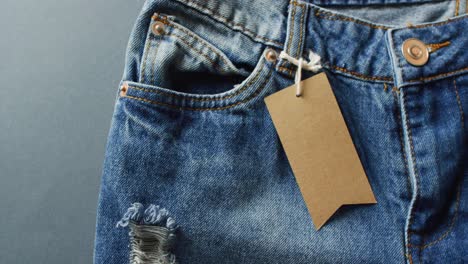 close up of jeans with tag on grey background with copy space