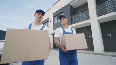 two young workers of removal company deliver boxes to a customer's home