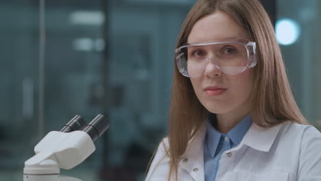 female expert of scientific laboratory working with microscope portrait of young woman in lab biology medicine and forensic expert practice