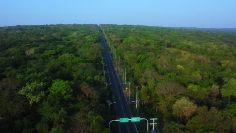 Luftaufnahme-Einer-Asphaltierten-Straße,-Laternen-Mit-Sonnenkollektoren,-Straße-Führt-Durch-Wald,-Paraguay