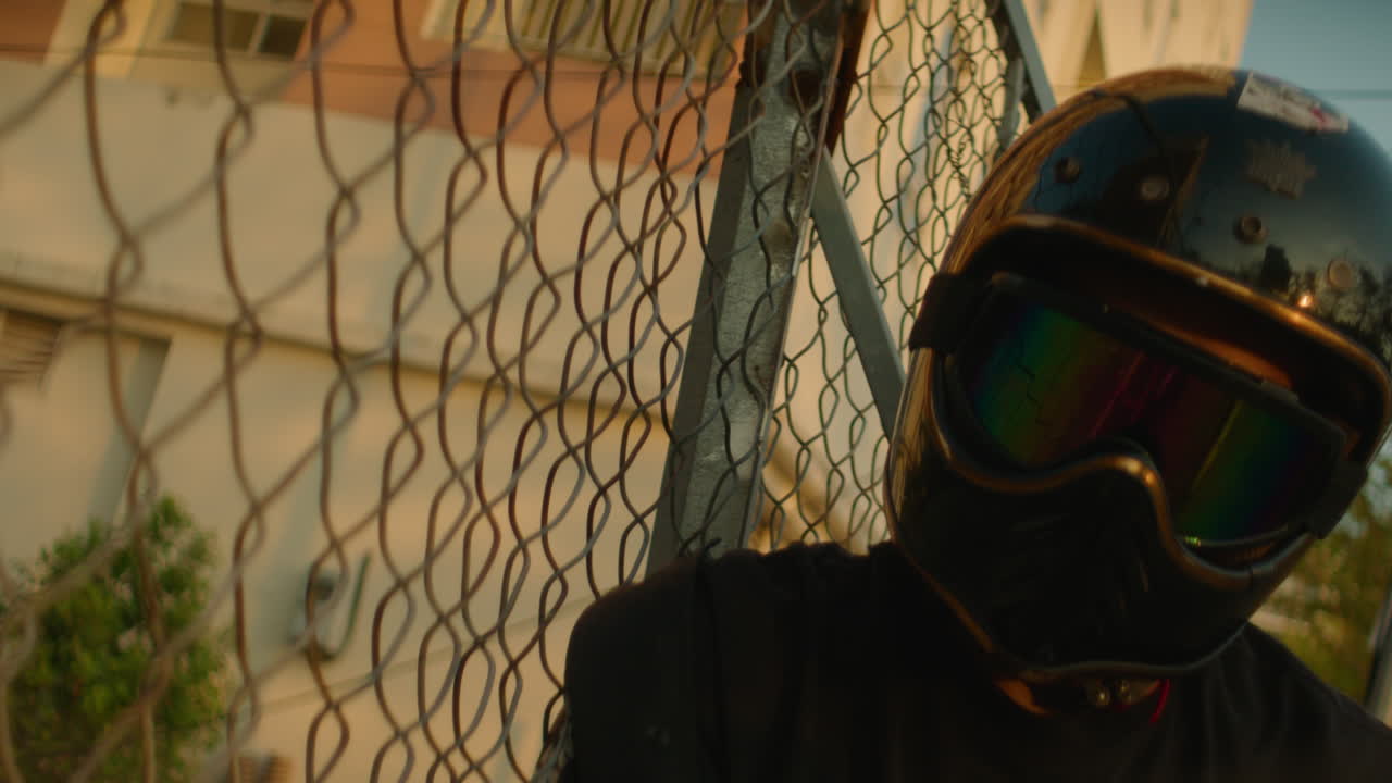 Person in Motorcycle Helmet Behind a Chain-Link Fence