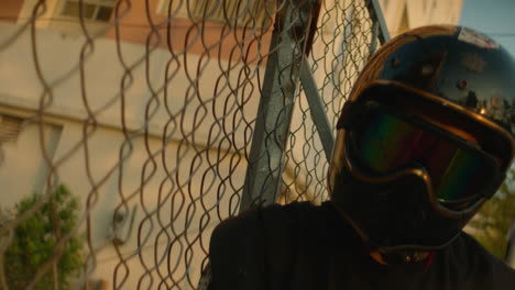 person in motorcycle helmet behind a chain-link fence