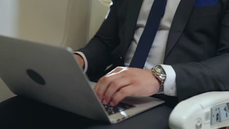 Young-businessman-using-laptop-computer-in-airplane