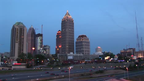 wolkenkrabbers vormen de achtergrond voor een panning shot in de schemering van het verkeer dat over een snelweg in atlanta stroomt