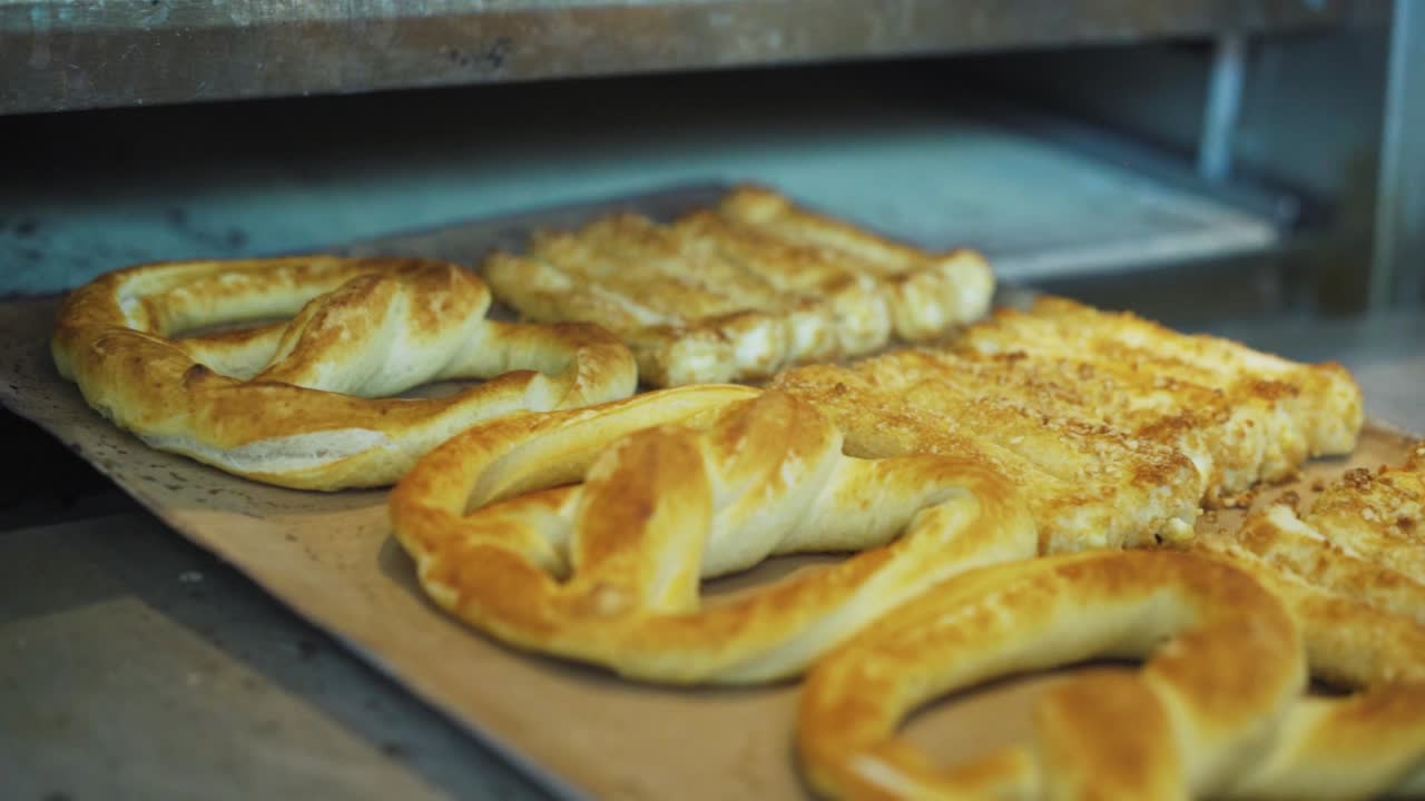 pan recién horneado y pretzels sacados del horno en una cocina de panadería - cierre, cámara lenta
