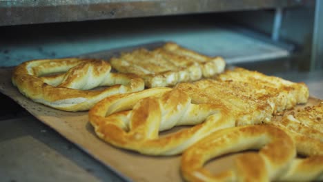 freshly baked bread and pretzels removed from the oven in a bakery kitchen - close up, slow motion