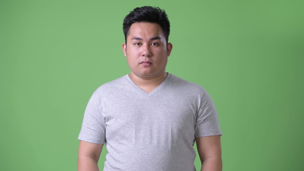 초록색 배경에 젊은 잘생긴 과체중 아시아인