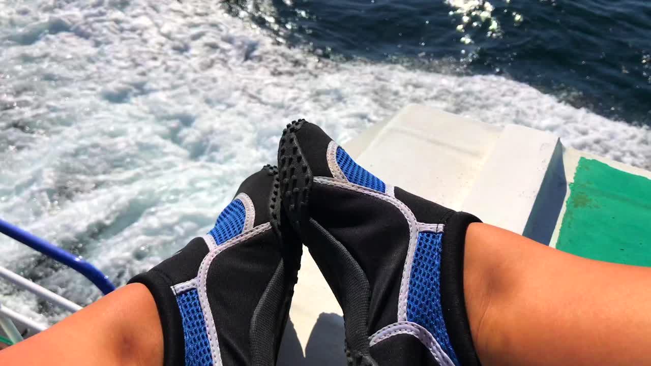 Feet in water shoes on a fast boat ride in Bali, Indonesia