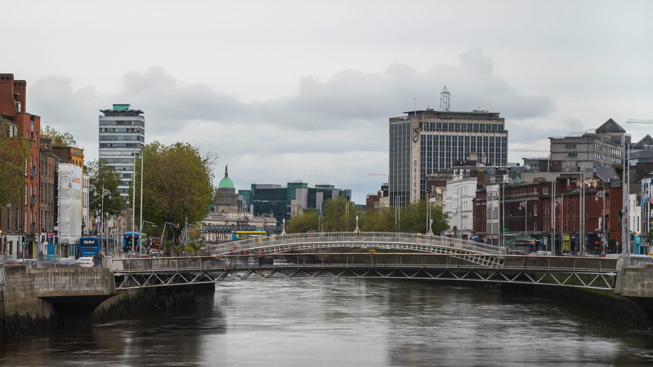 Tidsforløp av elven Liffey med folk som krysser broen og dagtrafikk og arkitektur langs elvebredden i Dublin by i Irland