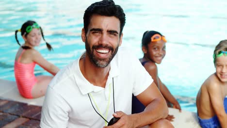 Male-trainer-smiling-near-poolside