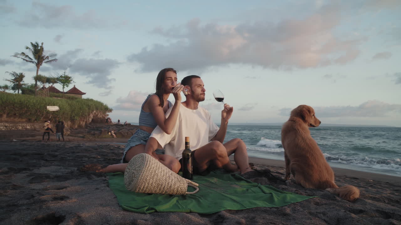 una pareja disfrutando del vino en la costa del océano.