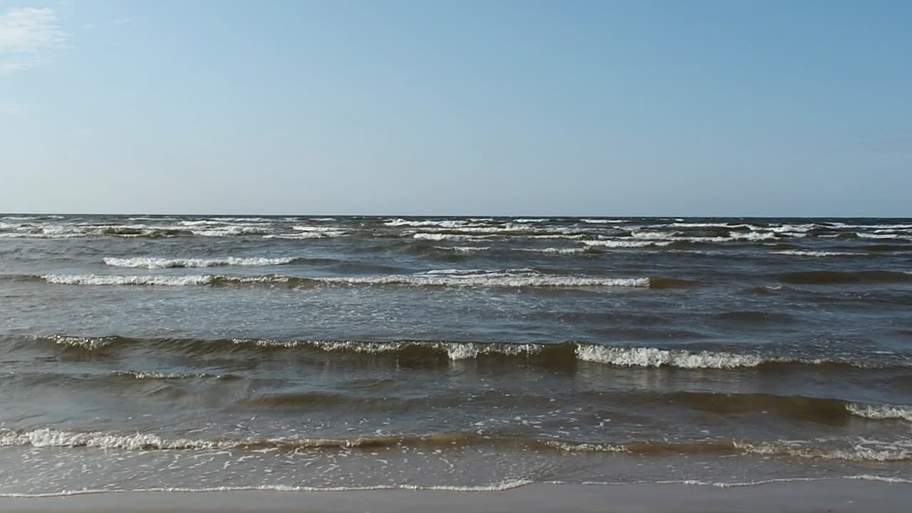 Slow Motion of Baltic Sea Waves on Latvian Beach Under Afternoon Sunlight