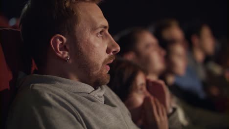 un joven se asusta mientras ve una película de terror. una película de miedo en el cine.