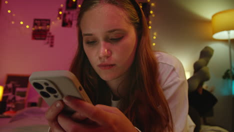 una mujer joven usando su teléfono en la cama.