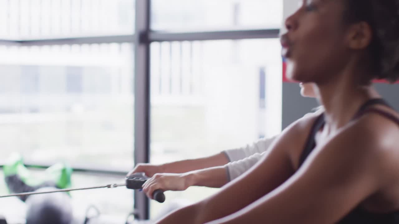 체육관 에서 운동 하는 로잉 기계 에 있는 결정적 인 백인 여성 의 비디오 측면 보기