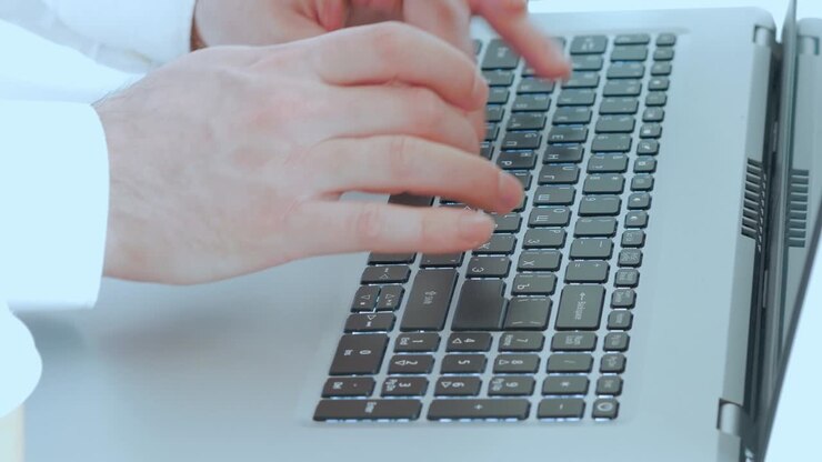 Close-up of male hands typing text on a laptop keyboard