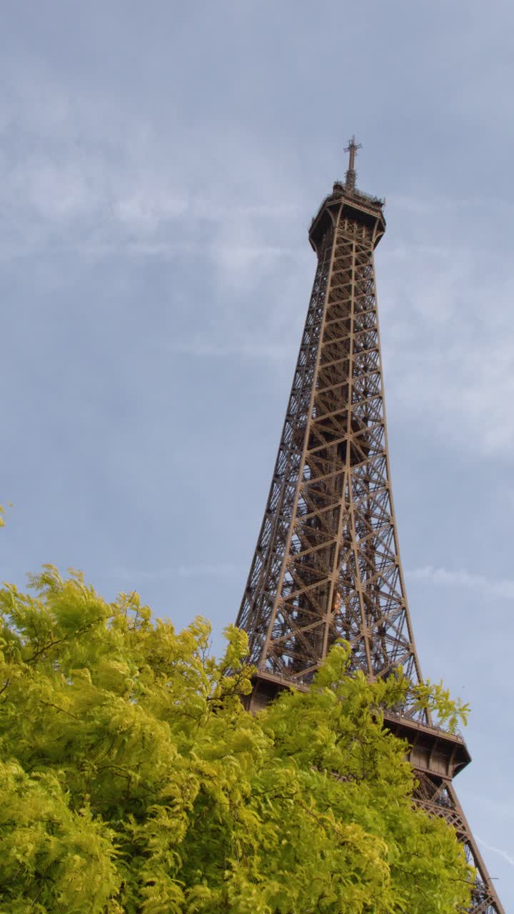 Inquadratura dal basso dell'iconica torre di ferro che si erge dietro un vibrante fogliame verde primaverile