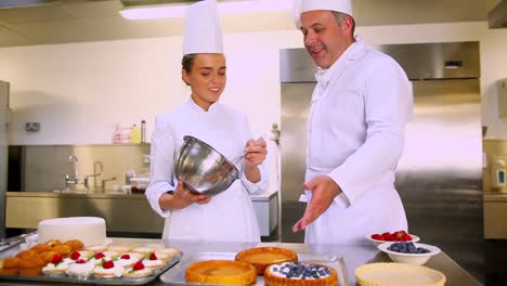 head chef teaching his student how to whisk cream