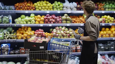 A-man-worker-in-a-black-apron-and-gloves-carries-out-a-inventory-of-goods-in-a-grocery-store