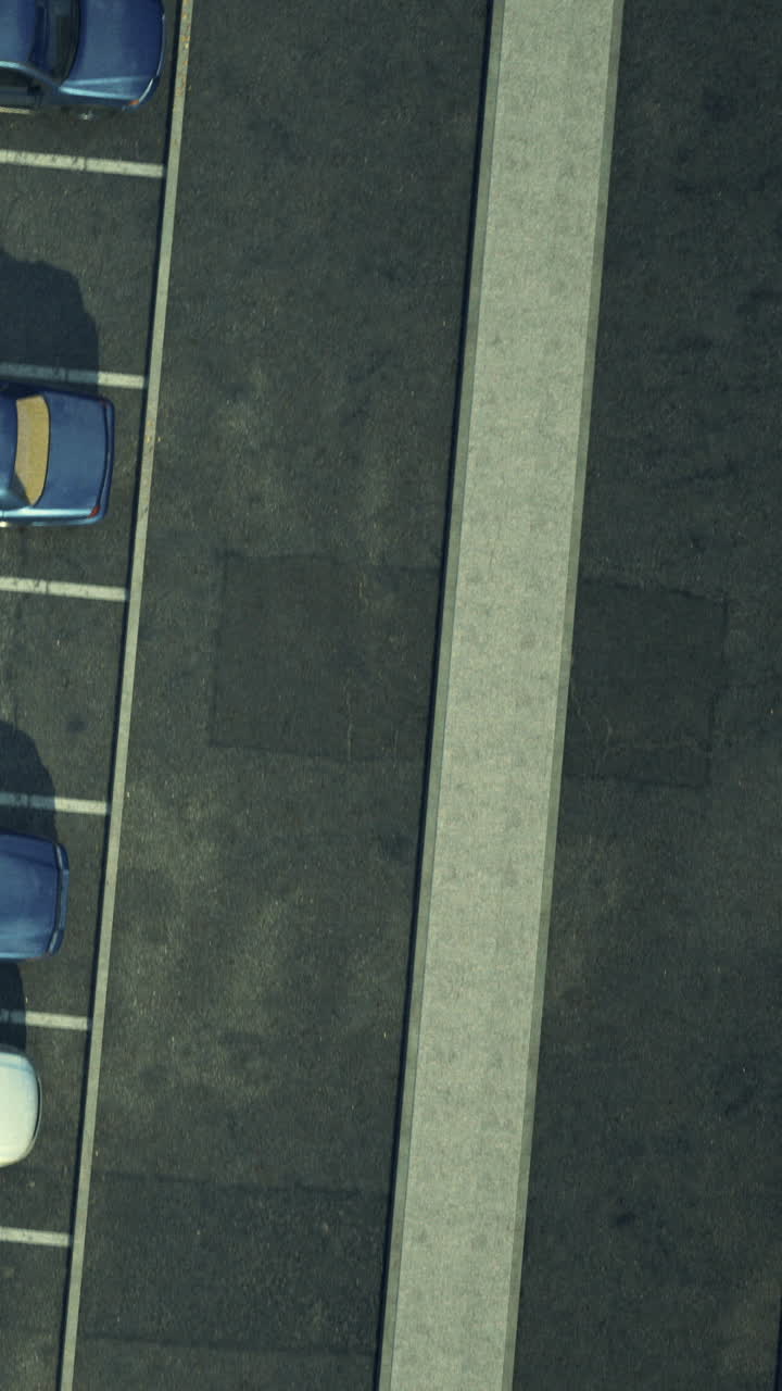 Cars parked in a lot with a long concrete strip in the middle at midday