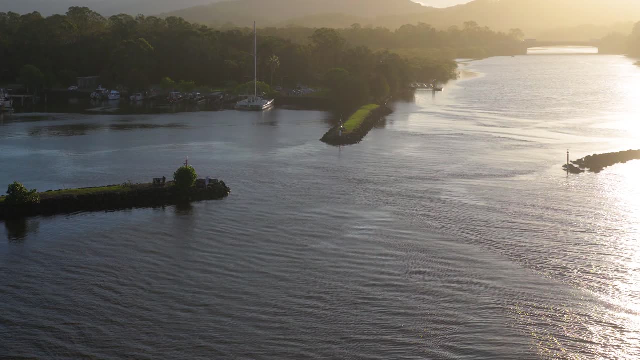 A tranquil river scene with boats and lush greenery, captured in soft, golden light. The camera smoothly pans over the water