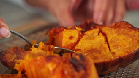 Nice-angle-of-spoon-dipping-into-pumpkin-preparing-for-ingredients-hands-in-shot