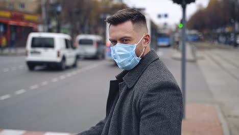 man in protective medical wear looking to the camera walking in the city. responsible behavior during world covid-19 pandemic.