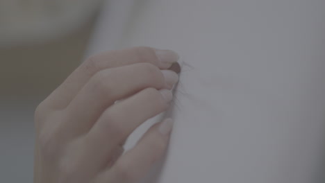 hand repairing a light gray fabric