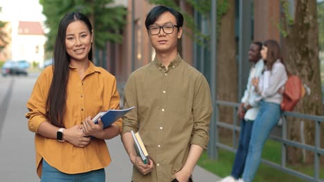 asian students looking at each other and at the camera in the street near the university