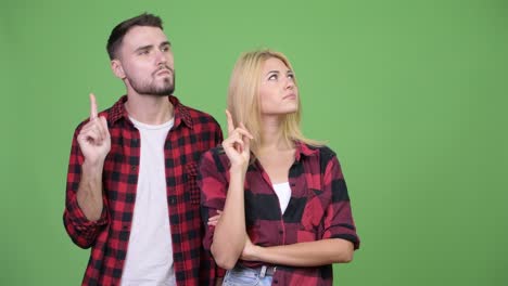 young couple pointing finger up together