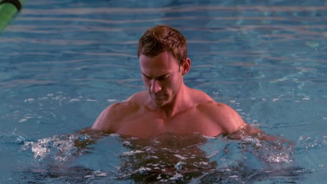 Muscular-man-working-out-with-foam-dumbbells-in-the-pool