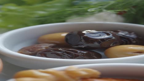 close-up of green and black olives in a small white bowl