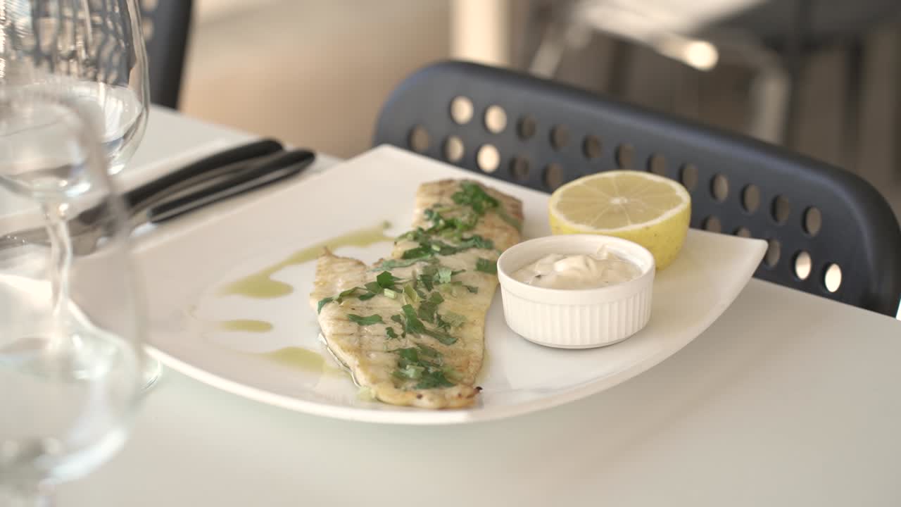 Delightful grilled fish served with lemon and creamy sauce at a cozy dining spot
