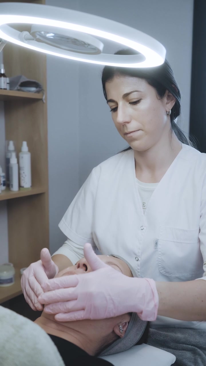 Esteticista realizando un masaje facial a un cliente en un spa