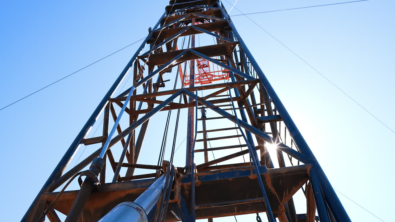 Metal ladder leading up to the derrick for natural resources production. Low angle view at the tower at drilling site.