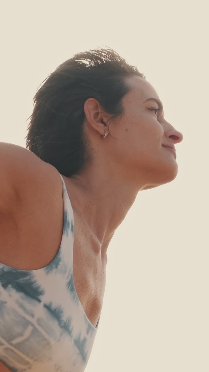 Primo piano di donna serena che si allunga all'aperto sotto la luce naturale