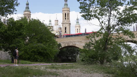 Man-Standing-Near-Puente-de-Piedra-With-Basilica-of-Our-Lady-of-the-Pillar-In-Zaragoza,-Spain