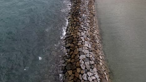 breakwater structure made of rocks near the coast with waves splashing