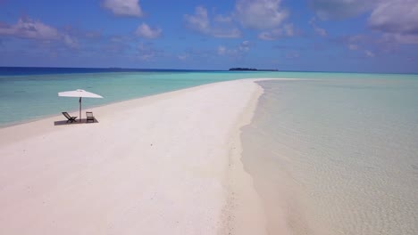 circular-aerial-view-of-the-white-beaches-of-the-turquoise-Caribbean-sea,-with-two-empty-wooden-seats-under-a-white-parasol