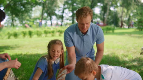 happy family preparing picnic in park. active summer rest on fresh air concept.