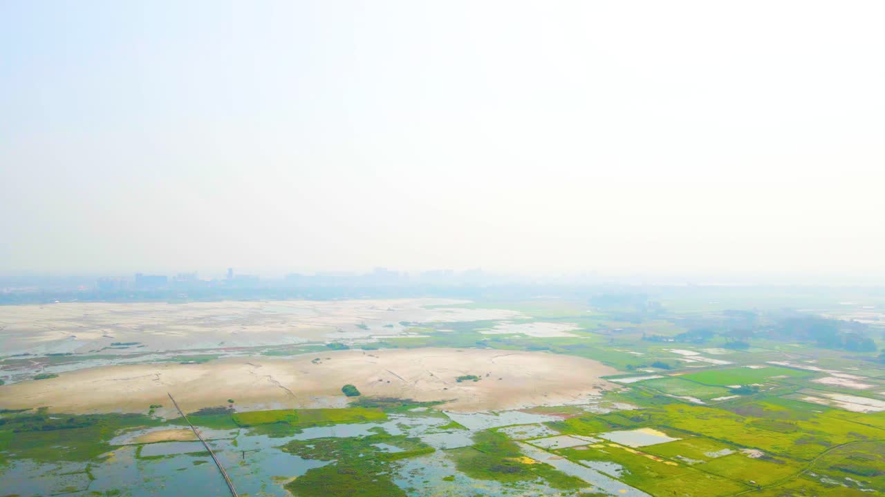 Wetland farms in green and vivid color with sand in drone ascend view