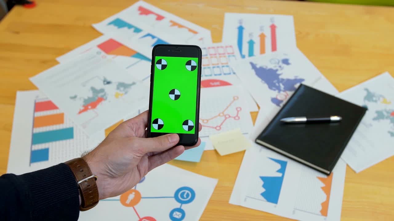 hombre usando teléfono inteligente con pantalla verde en el escritorio de la oficina, espacio de trabajo, buscar información