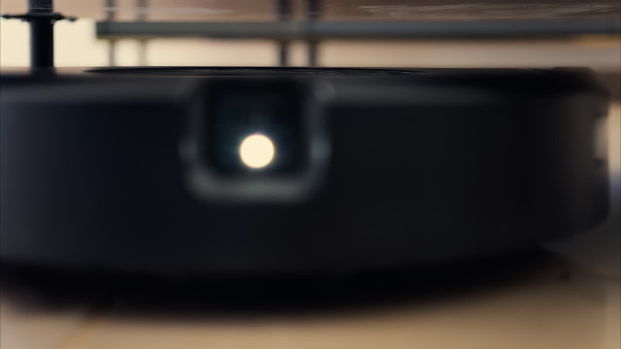 Close up of a black robot vacuum cleaner moving and rotating on the floor tiles