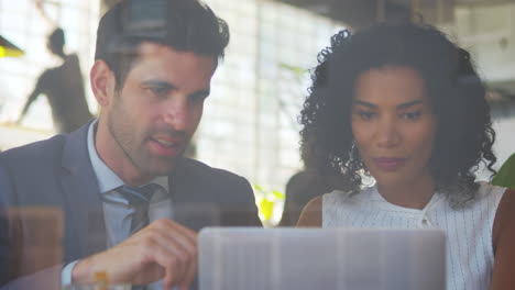 Two-Businesspeople-Meeting-In-Coffee-Shop-Shot-Through-Window