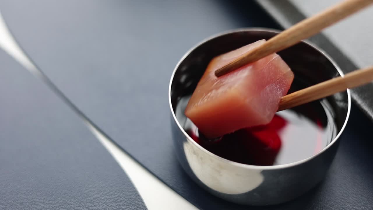 sashimi de atún sumergido en salsa con palillos