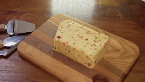 smoked gouda cheese with spicy red peppers is sliced on cutting board