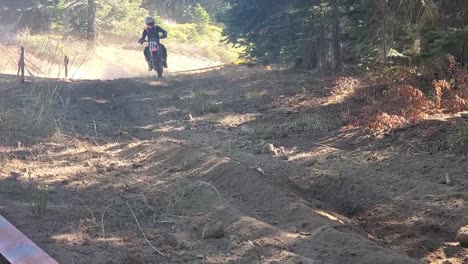 a dirt bike racer flys by camera with dust flying in the air