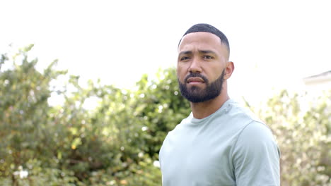 portrait of happy african american man smiling in sunny garden, copy space, slow motion