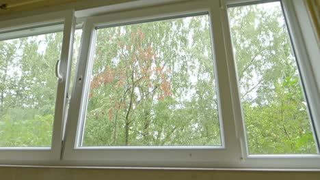 POV-walking-up-stairs-in-aparment-flat,-camera-stops-by-window-looking-out-trees